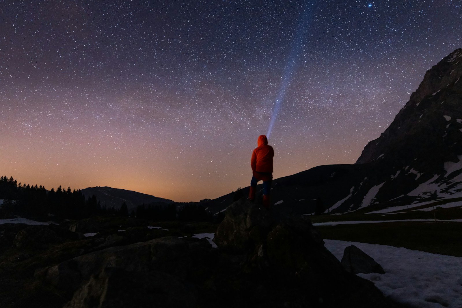Person with flashlight under starry night sky
